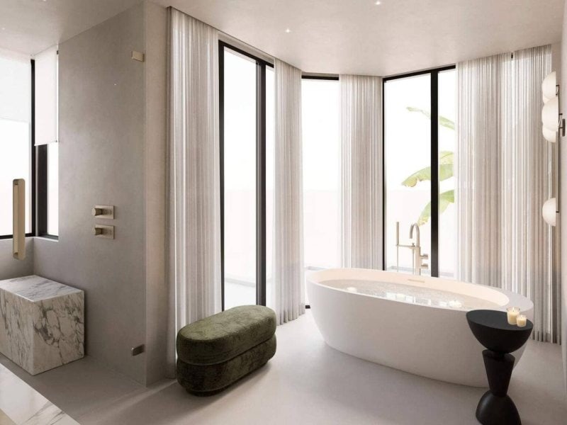 Freestanding tub in a serene Organic Modern bathroom with floor-to-ceiling sheers, microcement walls, and spa-inspired styling.