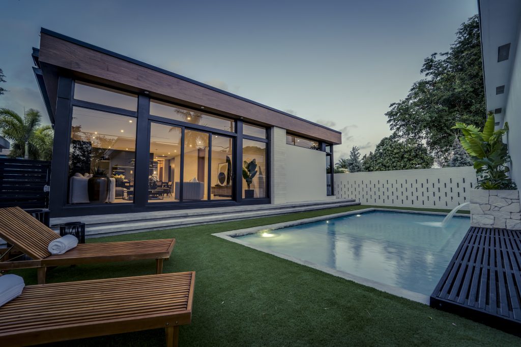 Midcentury modern pool and exterior view at dusk with lounger seating