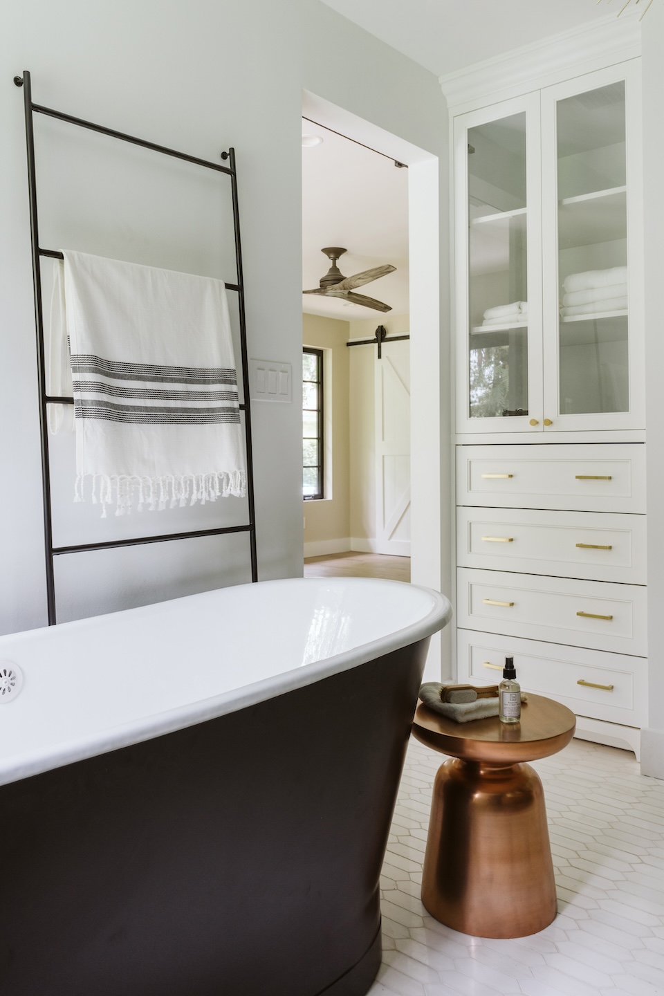 Parkland FL primary bath with black freestanding tub, brass hardware, and custom linen cabinet